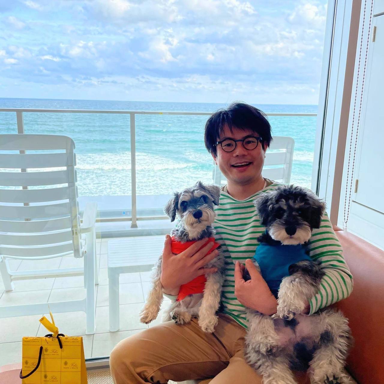 いぎカイロプラクティック院長・井木寿と愛犬のミニチュアシュナウザー２匹（ハナとポコ）。海辺のベランダにて撮影。